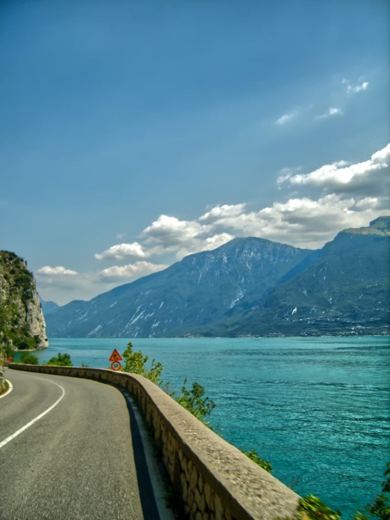 Road curving beside Lake Garda with mountains in the background